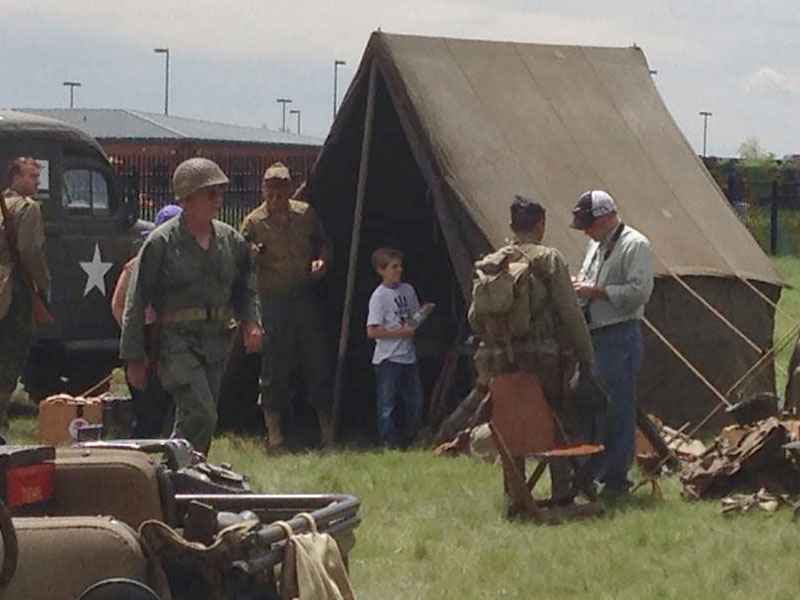 Six men and one child standing around outside a tent.